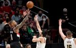 Portland Trail Blazers guard Damian Lillard, left, hits a shot over Denver Nuggets guard Facundo Campazzo, center, and center Nikola Jokic, right, during the first half of Game 4 of an NBA basketball first-round playoff series in Portland, Ore., Saturday, May 29, 2021.