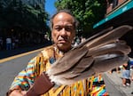An attendee of the Portland Pride parade wafts smoke around with feathers.
