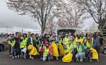La imagen muestra a más de 20 personas con chalecos amarillos brillantes. Muchas personas llevan bolsas de basura amarilla y pastillas de basura.