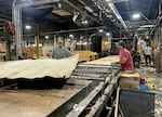 Employees lift slabs of wood through machinery at Freres Wood in Lyons on August 15, 2024. According to the company president, business has been rocky for mills across Oregon.