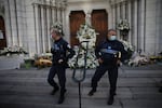 Municipal policemen stand guard outside Notre Dame church in Nice, France, Friday, Oct. 30, 2020. A new suspect is in custody in the investigation into a gruesome attack by a Tunisian man who killed three people in a French church. France heightened its security alert amid religious and geopolitical tensions around cartoons mocking the Muslim prophet.