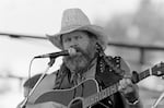 FILE - David Allan Coe, sporting Willie Nelson braids, performs at the Willie Nelson July 4th Picnic, on July 4, 1983 at Atlanta International Raceway in Hampton, Ga.
