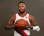 A basketball player in uniform looks at the camera while holding a ball.