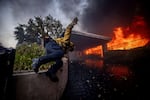 A firefighter jumps over a fence while fighting the Palisades Fire in the Pacific Palisades neighborhood of Los Angeles.