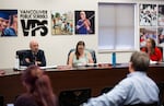 Three school board members sit side by side at a desk in front of an audience.