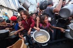 Palestinians shove to receive a hot meal from a charity kitchen in the Nuseirat refugee camp on Thursday.