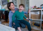 A woman is smiling at a child who is sitting on her laps inside an apartment.