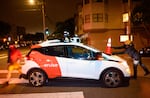 Members of Safe Street Rebel place a cone on a self-driving Cruise car in San Francisco.