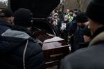 The coffin of boxing coach Mykhailo Korenovsky arrives at a cemetery where he's to be laid to rest after he died in the residential building that was hit in Dnipro in January.