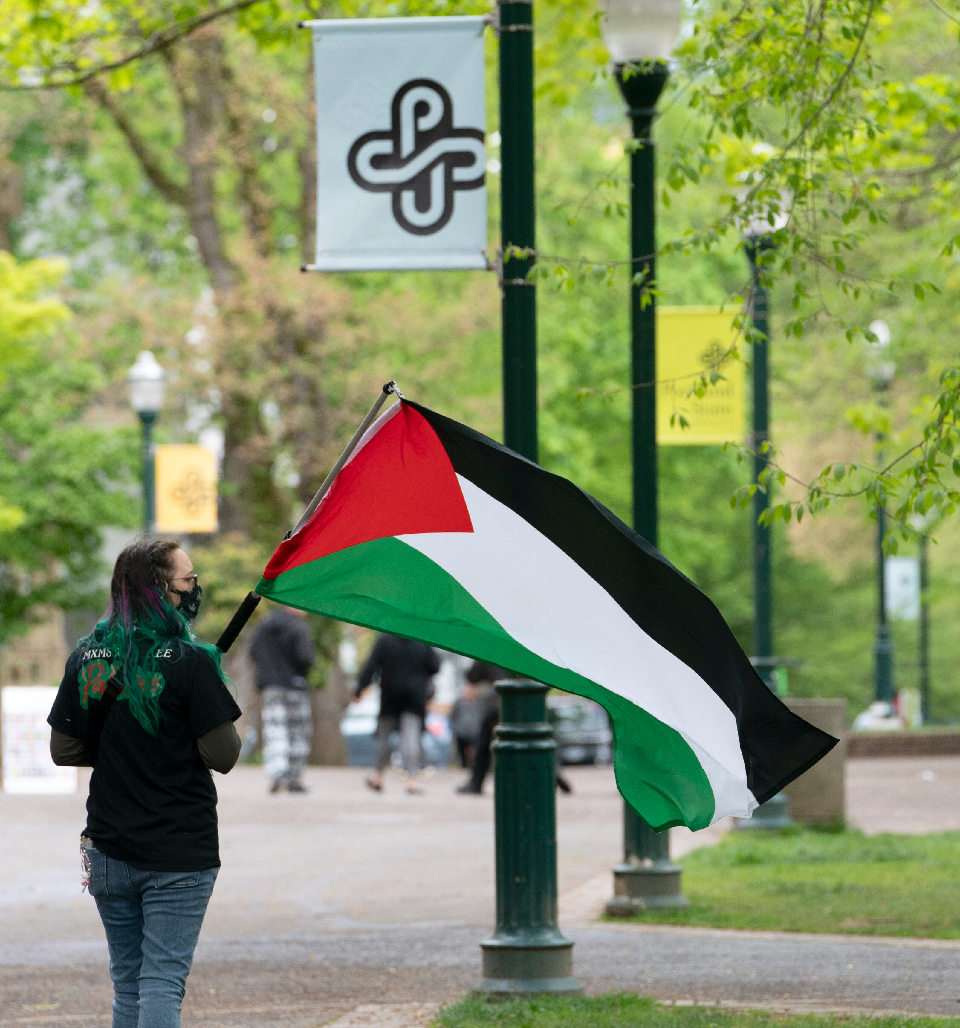 A protester carries a flag in Portland State Univeristy’s South Park Blocks, April 26, 2024. Protesters in support of Palestinians in Gaza and in protest of Portland State University’s ties with companies that have contracts with Israel, set up tents and barricades on Thursday and were removed by police after several hours. Police warned in a statement Friday morning that anybody occupying a closed park, engaging in violent activity, or destroying property could be arrested.