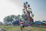 Two fairgoers walk past carnival rides at the Crook County Fair in Prineville, Ore., on Aug. 5, 2026. Attendance stayed light on opening day as wildfire smoke hung over the grounds, with many rides running at less than half occupancy.