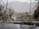 In this Sept. 20, 2017 file photo, electricity poles and lines lie toppled on the road after Hurricane Maria hit the eastern region of the island in Humacao, Puerto Rico.