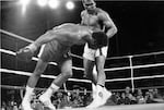 FILE - Muhammad Ali, right, watches as defending world champion George Foreman goes down to the canvas in the eighth round of their WBA/WBC championship match, on Oct. 30, 1974, in Kinshasa, Zaire.