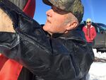 Terry Bencen ties an orange ribbon around a utility pole to symbolize unity for the Burns community.