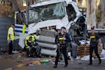 Israeli police and rescue services inspect the site where a truck driver rammed into a bus stop near an army base, wounding dozens of people, according to Israel's Magen David Adom rescue service in Ramat Hasharon, Israel, Sunday, Oct. 27, 2024.