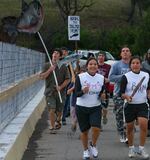 Salmon Run participants hold carved wooden salmon and signs that read "Bring the Salmon Home!"