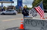 A person wearing a firefighter's helmet carried an American flag outside of a gathering of Proud Boys in Portland on Saturday, Sept. 26, 2020. Affixed to the flag was a sign that said "This flag belongs to all Americans, not some."