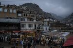 Dusk falls over Akre on Nowruz, a celebration of spring and renewal, and people gather in a central plaza. Mountains and homes loom over the plaza, which has twinkle lights strung up.