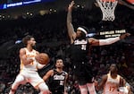 Atlanta Hawks guard Trae Young, left, looks to pass the ball against Portland Trail Blazers center Robert Williams III (35) as Trail Blazers forward Toumani Camara (33) defends during the first half of an NBA basketball game in Portland, Ore., Sunday, Nov. 17, 2024.