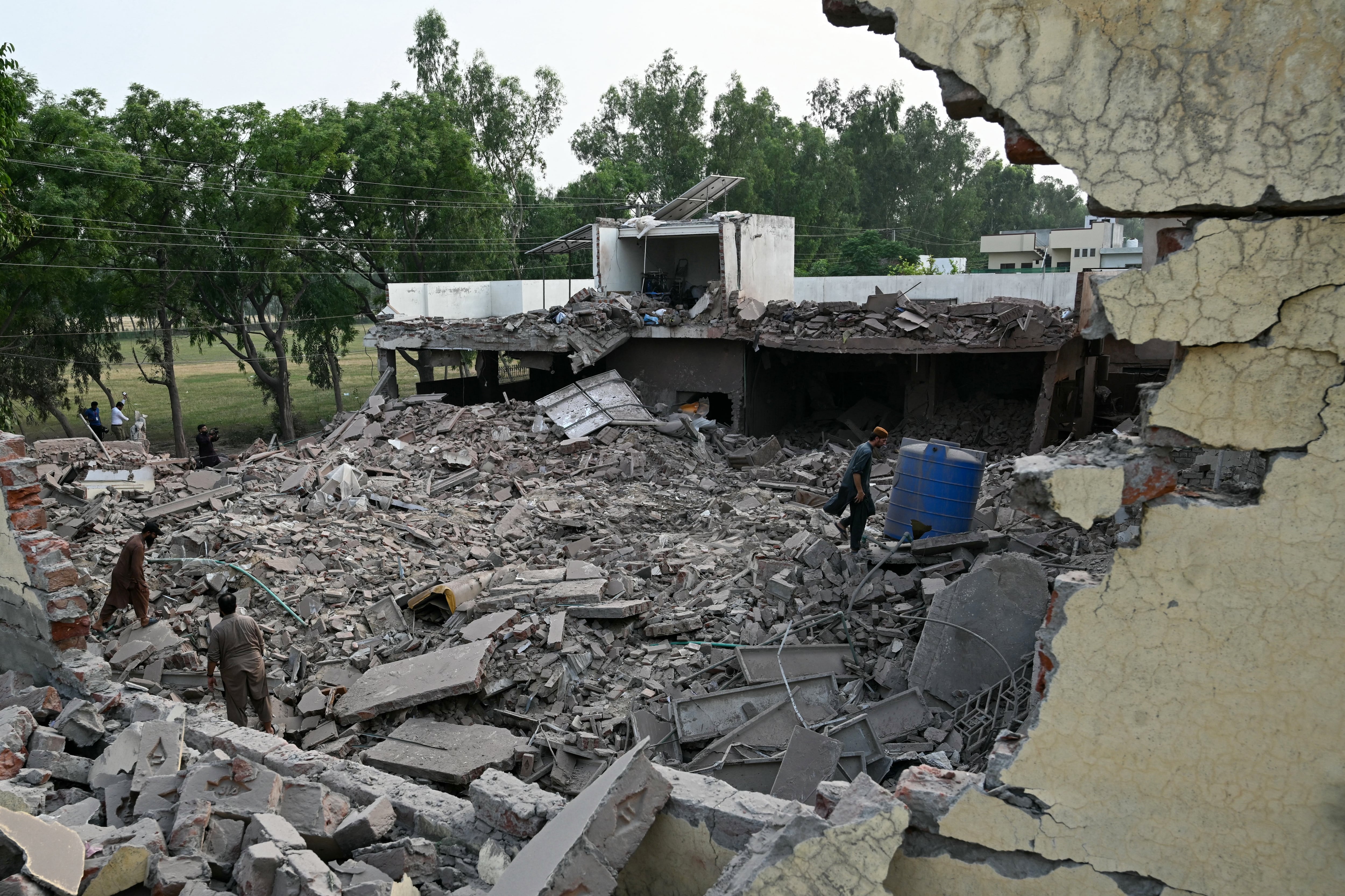Locals stand on the debris of destroyed structures at a government health and education complex in Muridke, Pakistan, on Wednesday, after Indian strikes.