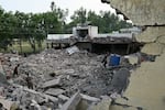 Locals stand on the debris of destroyed structures at a government health and education complex in Muridke, Pakistan, on Wednesday, after Indian strikes.