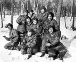 A group of women of color, dressed in military uniforms, pose in the snow.