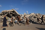 People, some carrying aid parcels, walk along the Salah al-Din road near the Nusseirat refugee camp in the central Gaza Strip, used by food-seeking Palestinians to reach an aid distribution point set up by the privately-run Gaza Humanitarian Foundation.