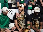Boston Celtics forward Jayson Tatum, center, holds the Larry O'Brien Championship Trophy as he celebrates with center Kristaps Porzingis, left, and guard Jaylen Brown, right, after the Celtics won the NBA championship with a Game 5 victory over the Dallas Mavericks on Monday in Boston.