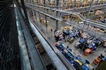 This photo shows the inside of DigiKey's warehouse, where employees fill orders for electronic components using an automated storage and retrieval system. The warehouse is filled with long conveyors and multiple workstations.