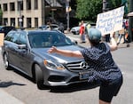 A protester yells at a vehicle arriving at the annual Portland Metro Chamber meeting at the Moda Center.