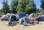 A woman searches for bottles at one of Grants Pass's city-owned homeless camps on June 11, 2025.