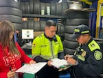 Police officers temporarily shut down a tire repair shop in Bogotá, Colombia on Tuesday. Tires fill the shelves behind them.