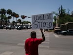 Alex Covarrubias, 32, holds up a sign at a street corner for the victims of Tuesday's shooting Robb Elementary School in Uvalde, Texas, Thursday, May 26, 2022.