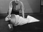 Claes Oldenburg sits on the floor near his oversized, soft-sculpture toothpaste tube at the Museum of Modern Art in New York City in 1964.