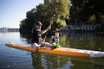 Man riding a paddle board with cat