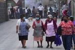Women walk on the ash-covered streets Monday in Santiago Xalitzintla.