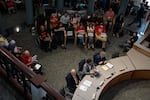 From left, lead city negotiator and a managing partner of Stafford Sports, LLC Carl Hirsh, deputy city administrator Donnie Oliveira and senior deputy city attorney Ken McGair sit at the dais as dozens of attendees hold up “No Bailouts for Billionaires” signs in protest of public funds going to the Moda Center during a Portland City Council meeting, in which the final vote on a “term sheet” is slated to happen, at Portland City Hall in Portland, Ore., on Aug. 12, 2026. The term sheet lays the framework for Moda Center lease negotiations with the Portland Trail Blazers.