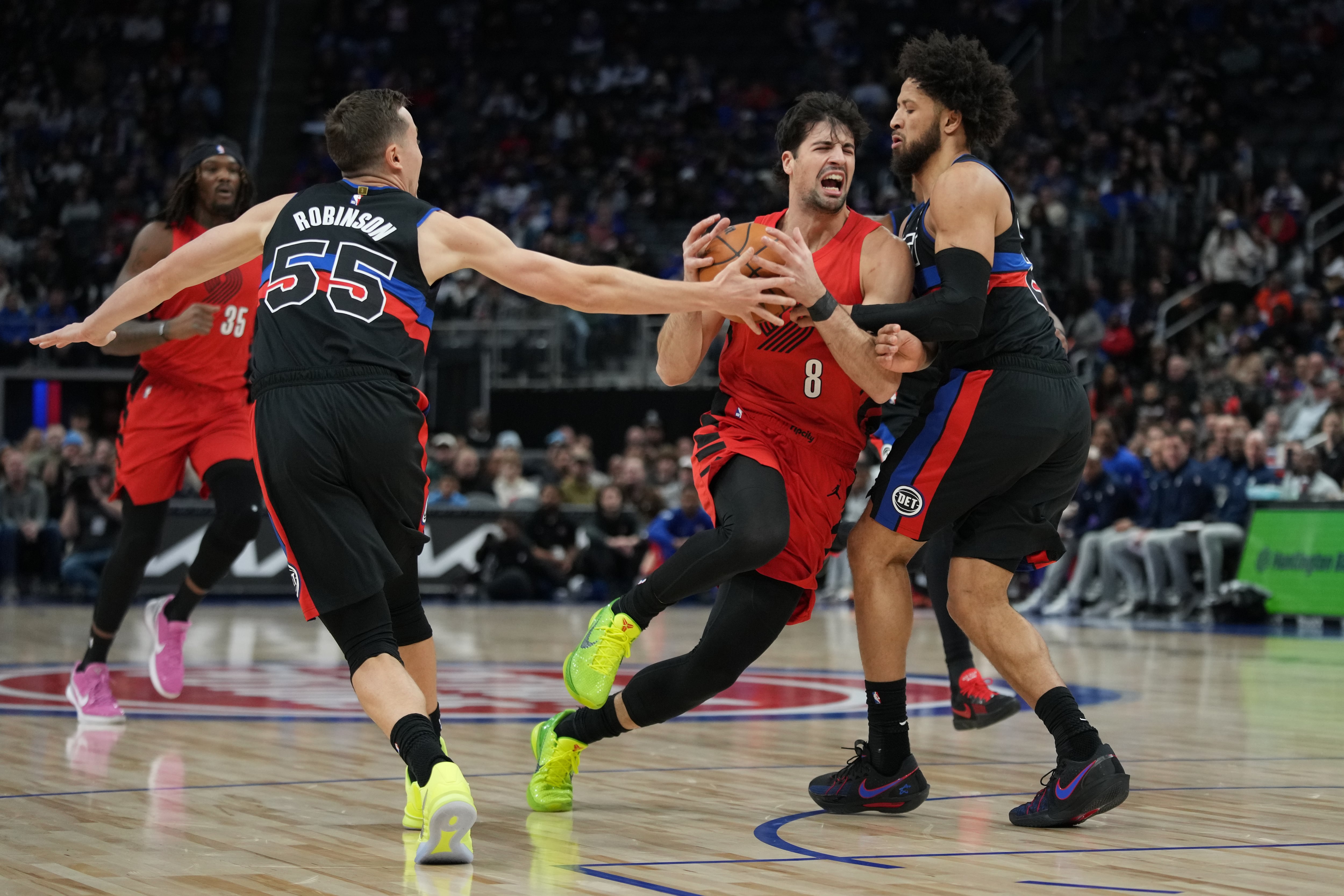 Portland Trail Blazers forward Deni Avdija, center, drives against Detroit Pistons forward Duncan Robinson, left, and guard Cade Cunningham during the first half of an NBA basketball game, Friday, Dec. 5, 2025, in Detroit.