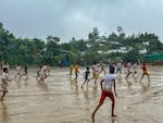 Rohingya refugee children play soccer in a December rain.