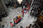 The coffin of Queen Elizabeth II with the Imperial State Crown resting on top is carried by the Bearer Party into Westminster Abbey.