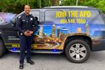 A police officer stands in front of an SUV painted with the skyline of Atlanta, Georgia, and the text "Join the APD 404.546.7650"
