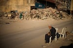 A man sits on a chair next to the rubble of a destroyed building in Iskenderun city, southern Turkey, Tuesday, Feb. 14, 2023. Thousands left homeless by a massive earthquake that struck Turkey and Syria a week ago packed into crowded tents or lined up in the streets for hot meals as the desperate search for survivors entered what was likely its last hours.