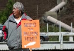During the third annual Salmon Run, an elder stands in front of Iron Gate Dam holding a "Bring the Salmon Home" sign.