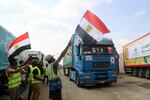 People on the Egyptian side of the Rafah border crossing wave flags as a convoy of lorries carrying humanitarian aid crosses to the Gaza Strip on Sunday.