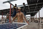 Workers install solar panels on the rooftop of a business.