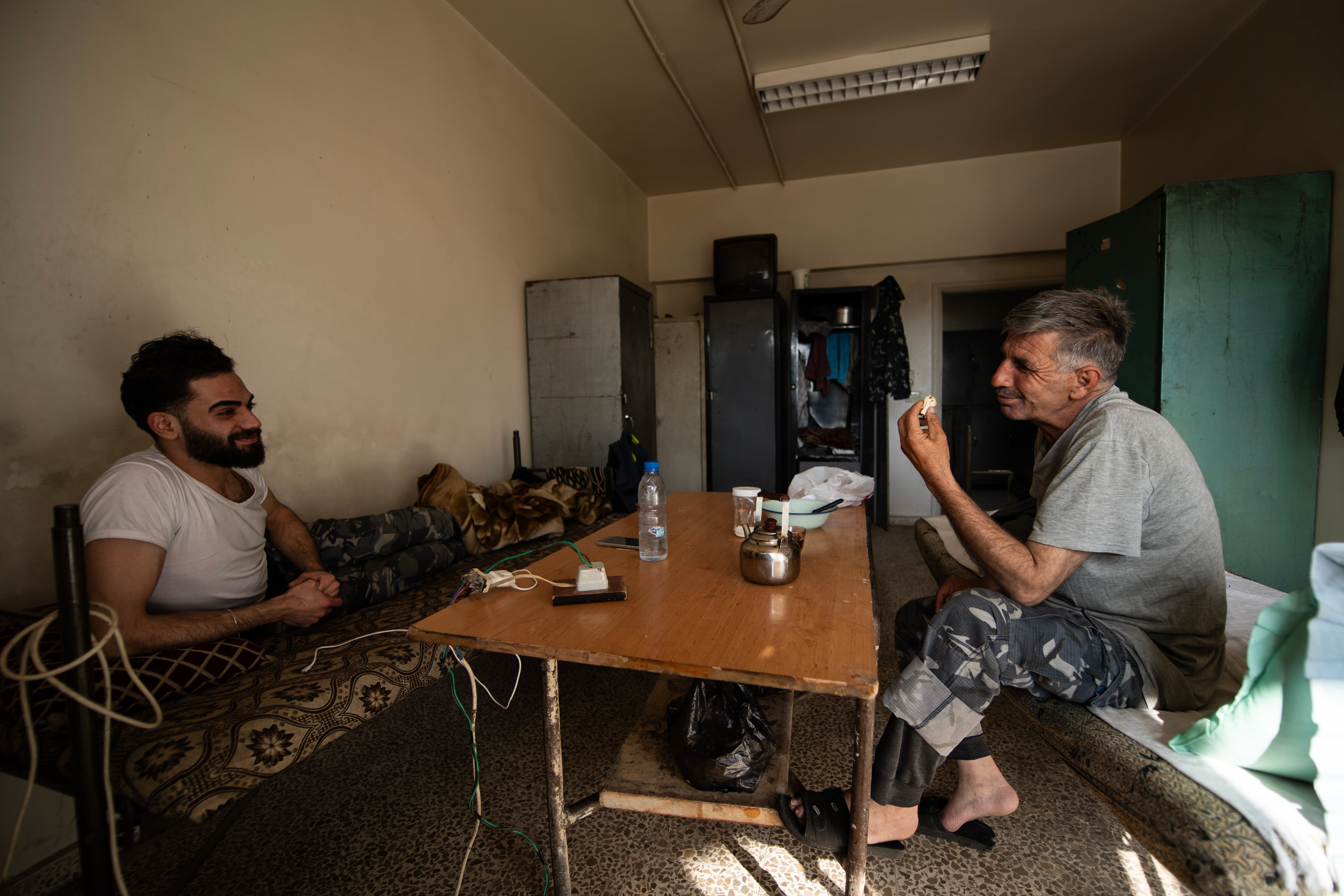 Firefighters Mohammed Khdeir and Mahdi Sliman have tea at their side of the firehouse.