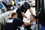 FILE: In this Nov. 2, 2017, photo, medics with the Cincinnati Fire Department work to keep a possible overdose victim awake after administering Naloxone while responding to a call at a gas station in downtown Cincinnati.