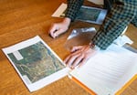 A man's hands on a table inspecting a map printed on computer paper.