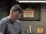 A sign hangs on the wall while a Scranton Army Ammunition Plant employee performs a hot inspection of metal parts.