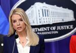 Attorney General Pam Bondi stands in front of a Department of Justice sign to deliver remarks. 